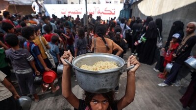 A Palestinian child walks away with a pot of rice obtained from a charity kitchen in the Nuseirat refugee camp in the central Gaza Strip, amid a UN-declared famine after nearly two years of war. (Eyad Baba/AFP) A Palestinian child walks away with a pot of rice obtained from a charity kitchen in the Nuseirat refugee camp in the central Gaza Strip, amid a UN-declared famine after nearly two years of war. (Eyad Baba/AFP)