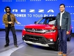 Bollywood actor Kartik Aaryan, left, poses for photographs next to a Brezza model at the Maruti stall during Bharat Mobility Global Expo 2025, in New Delhi.