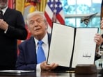 Donald Trump displays a signed executive order on gold card visa in the Oval Office 