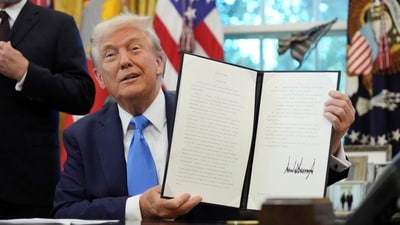 Donald Trump displays a signed executive order on gold card visa in the Oval Office (REUTERS)