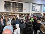 People stand in front of a departure board after a cyber attack caused delays at Brussels International Airport in Zaventem, Belgium.