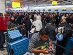 A man uses a smartphone as travellers queue to check in at Heathrow Airport Terminal 4, following a disruption to check-in and boarding systems caused by a cyber attack.