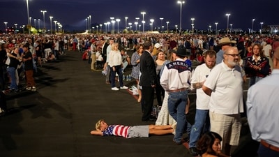 A boy lies on the ground wearing an American-flag themed shirt as people arrive, ahead of the morning sunlight, to attend a memorial service for slain conservative commentator Charlie Kirk at State Farm Stadium, in Glendale, Arizona, U.S., September 21, 2025.  REUTERS/Cheney Orr (REUTERS)