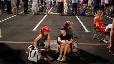 People sit on a towel as others queue, ahead of the morning sunlight, to attend a memorial service for slain conservative commentator Charlie Kirk at State Farm Stadium, in Glendale, Arizona, U.S., September 21, 2025.  REUTERS/Cheney Orr (REUTERS)