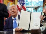 Donald Trump displays a signed executive order on gold card visa in the Oval Office 
