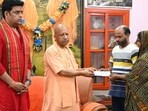 Uttar Pradesh CM Yogi Adityanath giving  <span class='webrupee'>₹</span>5 lakh cheque to the parents of the youth killed by cattle smugglers in Gorakhpur. (HT photo)