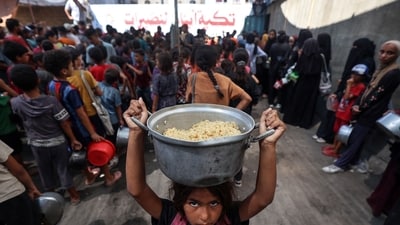 A Palestinian child walks away with a pot of rice obtained from a charity kitchen in the Nuseirat refugee camp in the central Gaza Strip, amid a UN-declared famine after nearly two years of war. (Eyad Baba/AFP) A Palestinian child walks away with a pot of rice obtained from a charity kitchen in the Nuseirat refugee camp in the central Gaza Strip, amid a UN-declared famine after nearly two years of war. (Eyad Baba/AFP)
