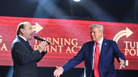 US President Donald Trump is greeted by singer Lee Greenwood as he arrives to speak at the public memorial service for right-wing activist Charlie Kirk in Arizona on Sunday.(Mandel Ngan/AFP)