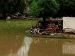 Residents sit outside a makeshift tent beside flooded field, following monsoon rains and rising water levels of the Chenab River in Punjab province, Pakistan.