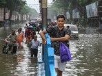 People make their way through a flooded road after heavy rainfall, in Kolkata on Tuesday, September 23