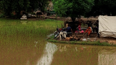 Residents sit outside a makeshift tent beside flooded field, following monsoon rains and rising water levels of the Chenab River in Punjab province, Pakistan. (REUTERS)