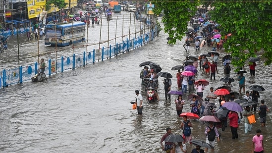 Commuters wade throught waterlogged roads in Kolkata under their umbrellas as rains continue to lash the city of joy since last night ahead of the state's biggest festival Durga Puja.(Samir Jana/Hindustan Times)