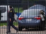 A law enforcement agent walks near a vehicle with a sign posted on the side near the scene of a shooting at a U.S. Immigration and Customs Enforcement office in Dallas on Wednesday, Sept. 24, 2025.