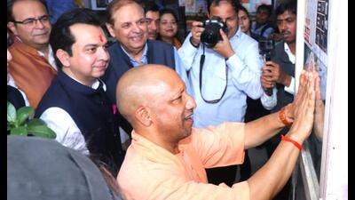 CM Yogi Adityanath sticks a GST handbill at a book store in Lucknow on Wednesday as part of the outreach drive. (HT)