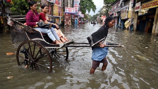 A hand rickshaw puller wades through knee-deep water after waterlogging on the streets of Kolkata.(Debajyoti Chakraborty/ANI)