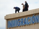 Law enforcement agents look around the roof of a building near the scene of a shooting at a U.S. Immigration and Customs Enforcement office in Dallas on Wednesday, Sept. 24, 2025.