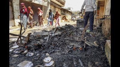 Gandhinagar: People walk past burnt shops following clashes and stone-pelting between two groups at Bahiyal village, in Gandhinagar district, Sept. 25 (PTI) Gandhinagar: People walk past burnt shops following clashes and stone-pelting between two groups at Bahiyal village, in Gandhinagar district, Sept. 25 (PTI)