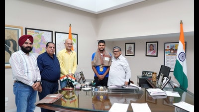 Punjab governor and UT administrator Gulab Chand Kataria felicitating Olympian Sanjay at the Punjab Raj Bhavan. Hockey Chandigarh president Karan Gilhotra was also present. (HT Photo)