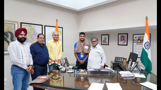 Punjab governor and UT administrator Gulab Chand Kataria felicitating Olympian Sanjay at the Punjab Raj Bhavan. Hockey Chandigarh president Karan Gilhotra was also present. (HT Photo)