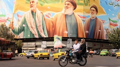 Iranians ride a motorcycle in front of a billboard depicting slain Lebanese Hezbollah leaders Hassan Nasrallah (C) and his successor Hashem Safieddine (R) as well as the late Iranian General Qasem Soleimani, in Tehran on September 28, 2025. (AFP) Iranians ride a motorcycle in front of a billboard depicting slain Lebanese Hezbollah leaders Hassan Nasrallah (C) and his successor Hashem Safieddine (R) as well as the late Iranian General Qasem Soleimani, in Tehran on September 28, 2025. (AFP)