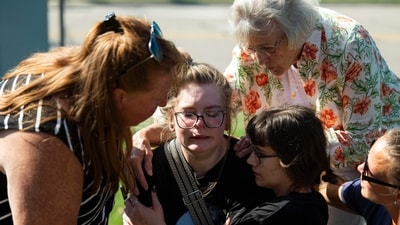 Joanne Green of Fenton, 75, top right, and McKenna Harrington of Davison, 25, second from right, comfort Katelyn Kruse of Fenton, 26, center, after Kruse was present at the scene of a shooting and structure fire at The Church of Jesus Christ of Latter-day Saints on McCandlish Road in Grand Blanc, Mich., Sunday, Sept. 28, 2025. (Katy Kildee/Detroit News via AP) (AP) Joanne Green of Fenton, 75, top right, and McKenna Harrington of Davison, 25, second from right, comfort Katelyn Kruse of Fenton, 26, center, after Kruse was present at the scene of a shooting and structure fire at The Church of Jesus Christ of Latter-day Saints on McCandlish Road in Grand Blanc, Mich., Sunday, Sept. 28, 2025. (Katy Kildee/Detroit News via AP) (AP)