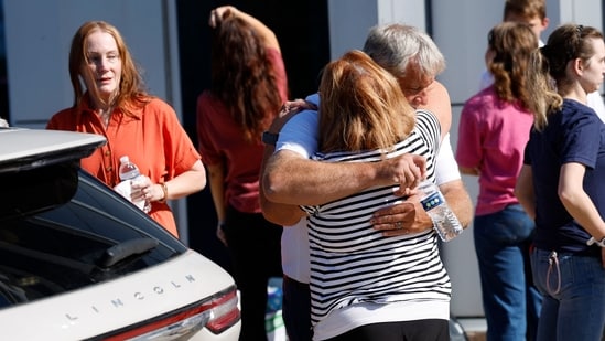 People hug near the reunification area outside of the NCG Cinema - Grand Blanc Trillium near the scene of a shooting at a church in Grand Blanc, Michigan, on September 28, 2025. At least four people were killed and several others injured Sunday after a shooter targeted a Mormon church in the US state of Michigan, where the building was also set on fire, authorities said. The suspect, a 40-year-old man from a nearby town, was shot dead by law enforcement after the attack, police said, without specifying any possible motive. (Photo by JEFF KOWALSKY / AFP)(AFP)