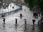 Commuters wade across a waterlogged street after heavy monsoon rains in Kolkata on 23 September 2025.