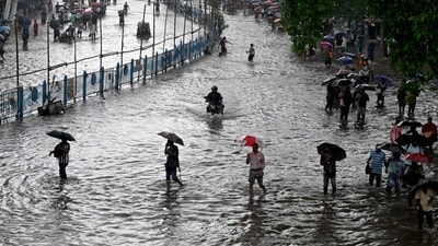 Commuters wade across a waterlogged street after heavy monsoon rains in Kolkata on 23 September 2025. (AFP)