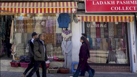 People walk past shops at a market during a four-hour relaxation in the curfew in Leh on Tuesday. (PTI Photo)