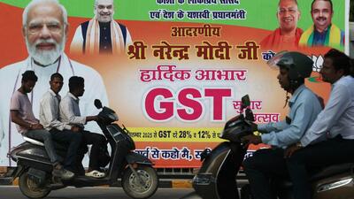 Commuters ride past a new Goods and Services Tax (GST) banner in Varanasi on September 24 (AFP) Commuters ride past a new Goods and Services Tax (GST) banner in Varanasi on September 24 (AFP)