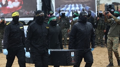 Hamas militants take pictures as fellow masked Palestinian fighters carry one of the coffins during the handover of the bodies of four Israeli hostages to the Red Cross in Khan Yunis in southern Gaza on February 20, 2025. (AFP) Hamas militants take pictures as fellow masked Palestinian fighters carry one of the coffins during the handover of the bodies of four Israeli hostages to the Red Cross in Khan Yunis in southern Gaza on February 20, 2025. (AFP)