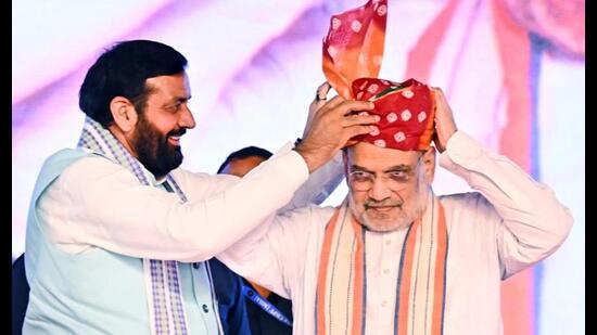 Haryana chief minister Nayab Singh Saini felicitates Union home minister Amit Shah with a safa during the state-level exhibition on new criminal laws in Kurukshetra on Friday. (PTI)