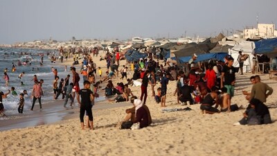 Displaced Palestinians sit on the beach in front of their tents as others swim in the Mediterranean sea in Khan Yunis in the southern Gaza Strip on October 3, 2025. (AFP) Displaced Palestinians sit on the beach in front of their tents as others swim in the Mediterranean sea in Khan Yunis in the southern Gaza Strip on October 3, 2025. (AFP)