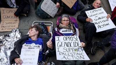 Protesters hold signs during a mass demonstration organised by Defend our Juries, against the British government's ban on Palestine Action, in London. (Reuters)