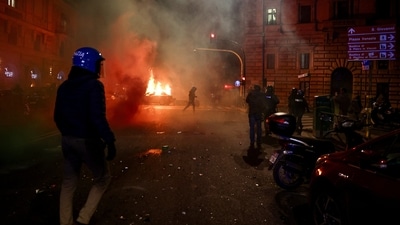 Police officers in riot gear gather as a vehicle burns in the background, during a national protest for Gaza in Rome, Italy. (Reuters)