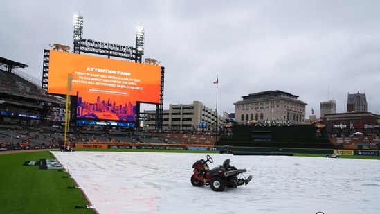 A tarp covers the field as rain falls while a message is seen on a video board alerting fans the start of Game 3 of baseball's American League Division Series between the Detroit Tigers and the Seattle Mariners will be delayed Tuesday, Oct. 7, 2025, in Detroit. (AP Photo/Ryan Sun)