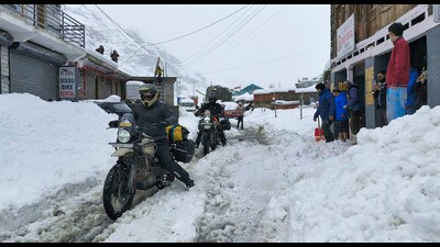 People ride their motorcycles through a snow-covered road at Sissu, in Lahaul -Spiti on Wednesday. (PTI)