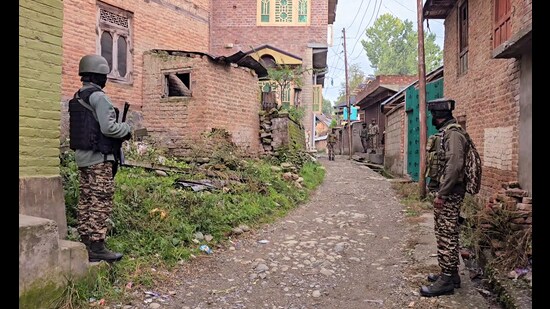 ecurity personnel stand guard as the state investigation agency raid is underway, in Kulgam on Wednesday. (ANI)