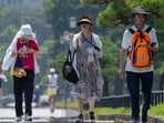 Tourists walk in the hot sun on a sidewalk near the Imperial Palace in Tokyo, Japan. (AFP)