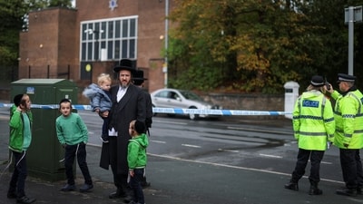 Ultra-Orthodox Jewish people stand next to police officers outside the Manchester synagogue, where multiple people were killed on Yom Kippur in what police have declared a terrorist incident, in north Manchester, Britain, October 5, 2025. REUTERS/Hannah McKay (REUTERS)