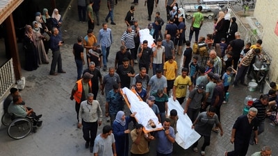 Mourners carry the bodies of Palestinians, who, according to medics, were killed in a deadly overnight Israeli strike on a building where displaced people were taking shelter. (REUTERS)