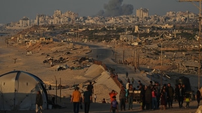 Displaced Palestinians walk along the coastal road, backdropped by smoke rising into the sky after an Israeli military strike in Gaza City (AP) Displaced Palestinians walk along the coastal road, backdropped by smoke rising into the sky after an Israeli military strike in Gaza City (AP)