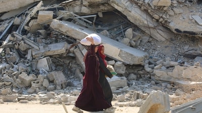 Palestinian women walk with bags of humanitarian aid they received at a distribution centre run by the US and Israeli-backed Gaza Humanitarian Foundation (GHF), (AFP) Palestinian women walk with bags of humanitarian aid they received at a distribution centre run by the US and Israeli-backed Gaza Humanitarian Foundation (GHF), (AFP)