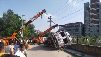 Police said the truck lost balance and toppled after a portion of the road caved in. Police said the truck lost balance and toppled after a portion of the road caved in.