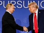 Donald Trump and Vladimir Putin shake hands during a press conference.