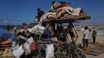 Displaced Palestinians sit and stand next to their belongings piled on a motorcycle near Wadi Gaza in the central Gaza Strip after the announcement of a ceasefire. (AP) Displaced Palestinians sit and stand next to their belongings piled on a motorcycle near Wadi Gaza in the central Gaza Strip after the announcement of a ceasefire. (AP)