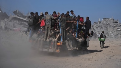 Displaced Palestinians ride on the back of a truck past destroyed buildings as they return to their homes in the Zeitoun neighbourhood of Gaza City on Friday, October 10 (AP) Displaced Palestinians ride on the back of a truck past destroyed buildings as they return to their homes in the Zeitoun neighbourhood of Gaza City on Friday, October 10 (AP)