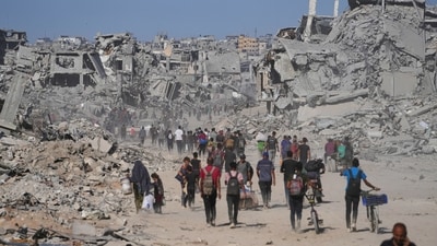 Displaced Palestinians walk past destroyed buildings as they return to their homes in the Zeitoun neighborhood of Gaza City. (AP) Displaced Palestinians walk past destroyed buildings as they return to their homes in the Zeitoun neighborhood of Gaza City. (AP)