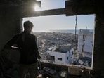 A man looks out from his damaged apartment at the destruction in his neighborhood in Gaza City, Friday, Oct. 10, 2025, after returning home following an agreement between Israel and Hamas on a ceasefire and the release of remaining hostages. 