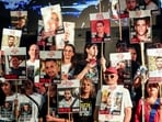 People hold placards with pictures of hostages who taken hostage in the deadly October 7, 2023 attack by Hamas.